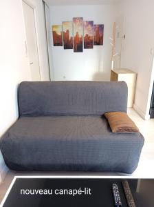 a couch in a living room with a remote control at Ravissant Appartement T2 proche centre-ville avec loggia in Villefranche-sur-Saône +21 photos