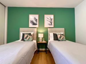 twee bedden in een kamer met groene muren bij Domus Vallis in Furnas