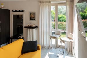 - un salon avec un canapé jaune et une fenêtre dans l'établissement Sant'Anna Villetta Giardino - Pianello del Lario by LoveComo, à Pianello Del Lario