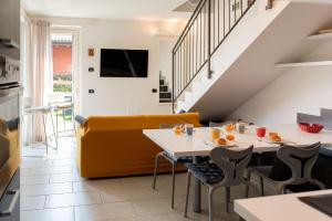 une salle à manger avec un canapé jaune et une table dans l'établissement Sant'Anna Villetta Giardino - Pianello del Lario by LoveComo, à Pianello Del Lario