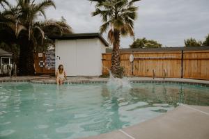 Eine Frau sitzt im Wasser eines Schwimmbeckens. in der Unterkunft Triangle Motel in Red Bluff