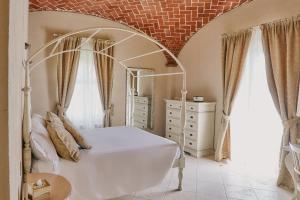 a bedroom with a white bed and a brick wall at Tenuta Montemagno Relais & Wines in Montemagno