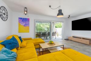 a living room with a yellow couch and a flat screen tv at Villa Maša in Rovinj