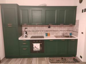 una cucina con armadi verdi e lavandino di Maison Cocò ad Aosta