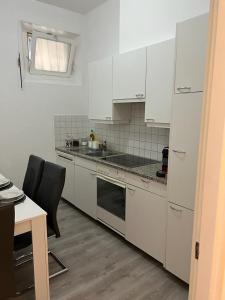 een keuken met witte apparatuur en een tafel en stoelen bij B&B Ilien in Bellinzona