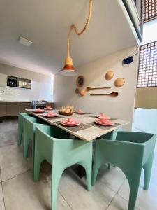 una cucina con un lungo tavolo con sedie verdi di Casa Oiti: à Beira-Mar de Tambaú na melhor localização de João Pessoa - Piscina, Aconchego e Lazer a João Pessoa