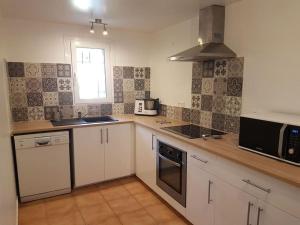 a kitchen with white cabinets and a sink and a microwave at Partie de mas en campagne in Eyragues +11 photos