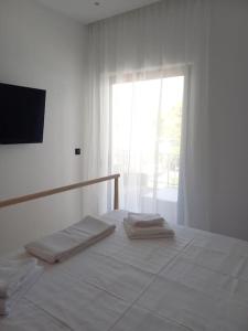 a white bedroom with a bed with two folded towels at Kepesis Apartment in Agioi Theodoroi
