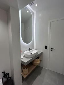 a white bathroom with a sink and a mirror at Kepesis Apartment in Agioi Theodoroi +17 photos