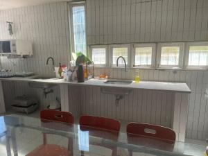 eine Küche mit Spüle und Theke mit roten Stühlen in der Unterkunft Casa Pê na Areia e Vista ao Mar em São José in São José da Coroa Grande + 34 Fotos