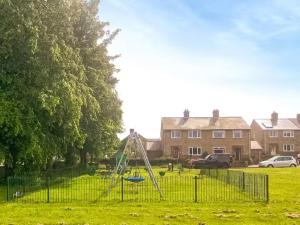 a park with a swing set in the grass at Glebeside House in Satley