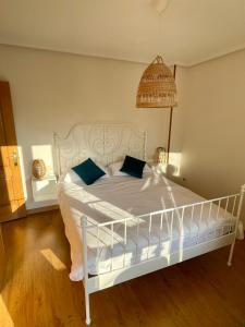 a bedroom with a white bed with blue pillows at La Santina y su Jardín in Avilés