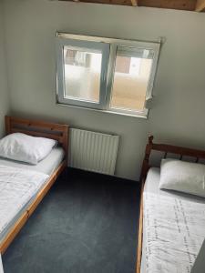 twee bedden in een kleine kamer met twee ramen bij Mooie chalet met grote tuin dichtbij Amsterdam in Opmeer