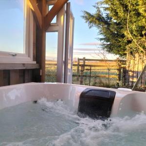 The Granary Thirsk Luxury Holiday Cottage Barn في ثيرسك: حوض استحمام بالماء مع نافذة