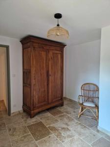 a room with a wooden cabinet and a chair at Logement privé avec terrasse in Chanonat