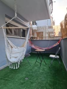 a hammock and a chair in a room with green grass at Relax an' Chill in Thessaloniki