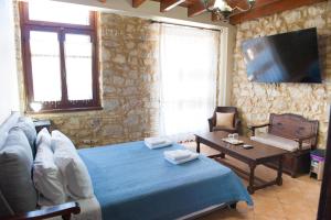 a bedroom with a bed and a couch and a table at SeaFront Stone Suites in Vonitsa