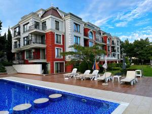 a pool in front of a building with chairs and a building at Sweet home in Varna City