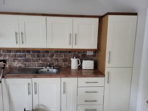 a kitchen with white cabinets and a sink at Holiday House in Galway