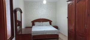 a bedroom with a bed with a wooden headboard and a mirror at Appartement vu plage kemado in Al Hoceïma