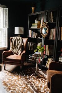 a living room with a chair and a book shelf with books at The Federal Inn in Maumee