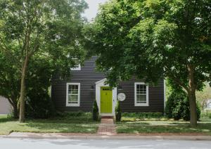 a black house with a yellow door and trees at The Federal Inn in Maumee