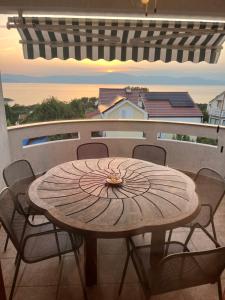 a wooden table and chairs on a balcony with a view at Apartments Hanka in Njivice