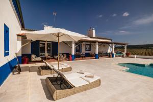 a patio with chairs and an umbrella and a pool at Monte do Melo in Montemor-o-Novo