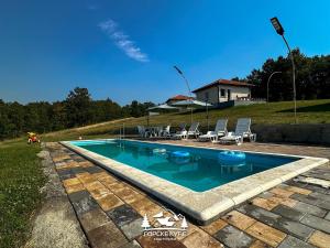 a swimming pool with chairs and a house in the background at Gorske Kuće in Koštunići