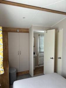 a bedroom with white walls and a bed and a bathroom at Nirvana, Smells Like Holiday Spirit, West Sands in Selsey
