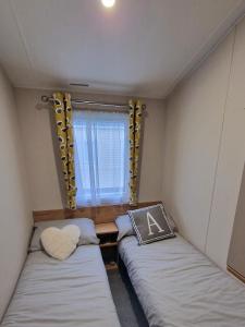 two beds in a small room with a window at Nirvana, Smells Like Holiday Spirit, West Sands in Selsey