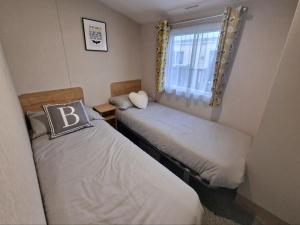 two beds in a small room with a window at Nirvana, Smells Like Holiday Spirit, West Sands in Selsey +4 photos
