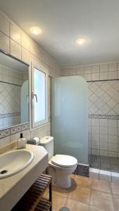 ein Badezimmer mit Toilette, Waschbecken und Spiegel in der Unterkunft Casa Angela in Corralejo + 11 Fotos