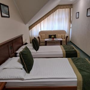 a hotel room with two beds and a couch at Kígyósi Csárda & Panzió in Fülöpszállás
