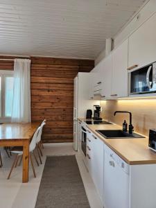 a kitchen with white cabinets and a wooden table at Rauhallinen asunto maalla, navetan päädyssä. in Muurame +5 photos