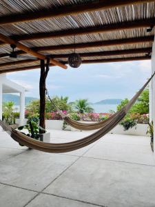 a hammock on a patio with a view of the ocean at Casa A la Mar in Zihuatanejo