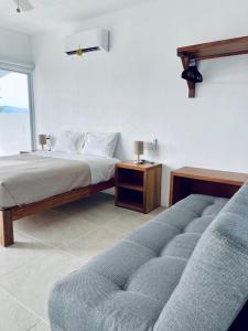 a bedroom with a bed and a couch and a window at Casa A la Mar in Zihuatanejo