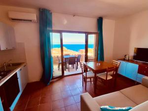 Una sala de estar con cocina y una mesa con sillas. en Costa Paradiso Villaggio maya GP 2 15 Bilocale vista mare, en Costa Paradiso
