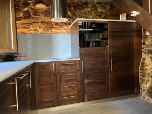 a kitchen with wooden cabinets and a microwave at La Casina de Gelo in Riego de Ambros