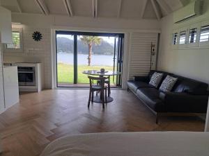 a living room with a couch and a table at Waterfront luxury tiny house in Tairua