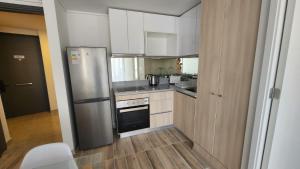 Una cocina con gabinetes blancos y un refrigerador de acero inoxidable. en Laguna del mar, La Serena, en La Serena