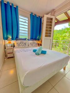 - une chambre avec un lit doté de rideaux bleus et d'une fenêtre dans l'établissement Gran Bwa la villa west indies, à Sainte-Luce