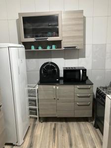 eine Küche mit einer Mikrowelle und einem Kühlschrank in der Unterkunft Casa de praia in Caraguatatuba