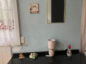 Zimmer mit einem Tisch, einer Lampe und einem Spiegel in der Unterkunft Casa de praia in Caraguatatuba