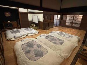 2 ampi letti in una camera con pavimenti in legno di 昭和体験宿Rin a Hokota
