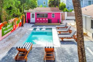 una piscina con sillas y una casa rosa en Salt Gypsy Unit A Expansive Outdoor Space w Pool, en Tybee Island