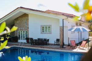 a house with a pool and chairs and an umbrella at The Oak´S Wolf-Country House in Fafe