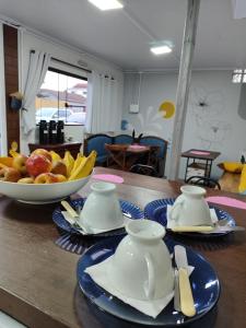 a table with a bowl of fruit and a plate of food at Maga hospedagem in Penha