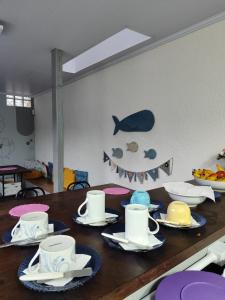 a table with plates and cups on top of it at Maga hospedagem in Penha