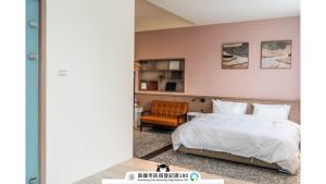 una camera da letto con un letto bianco e una sedia di Yi Hostel a Kaohsiung
